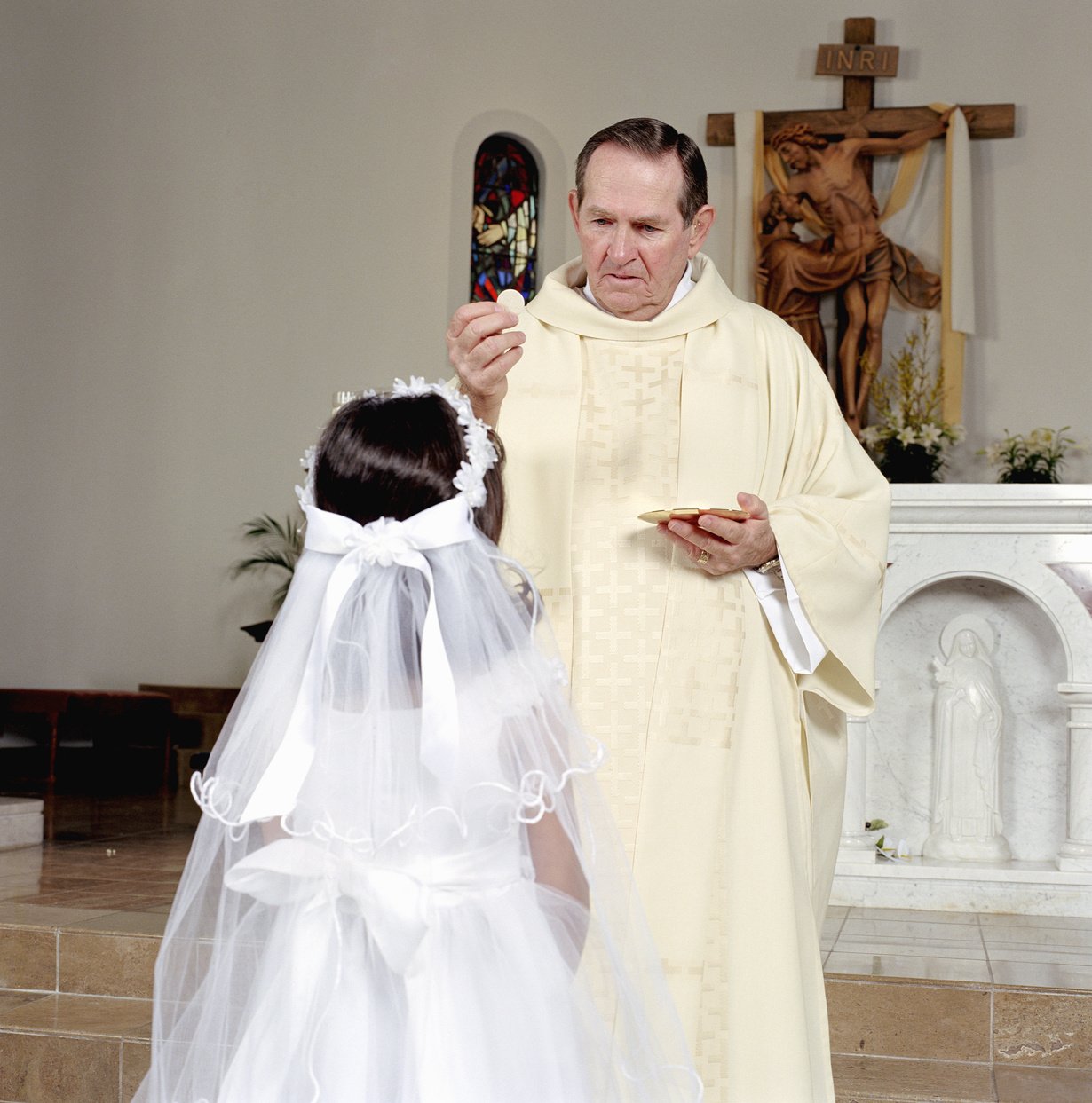 Girl (5-7) receiving communion bread at first holy communion