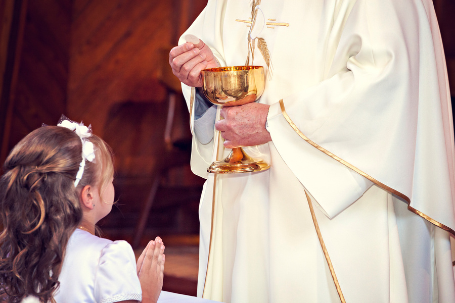 Communion and clergyman. First Holy Communion.